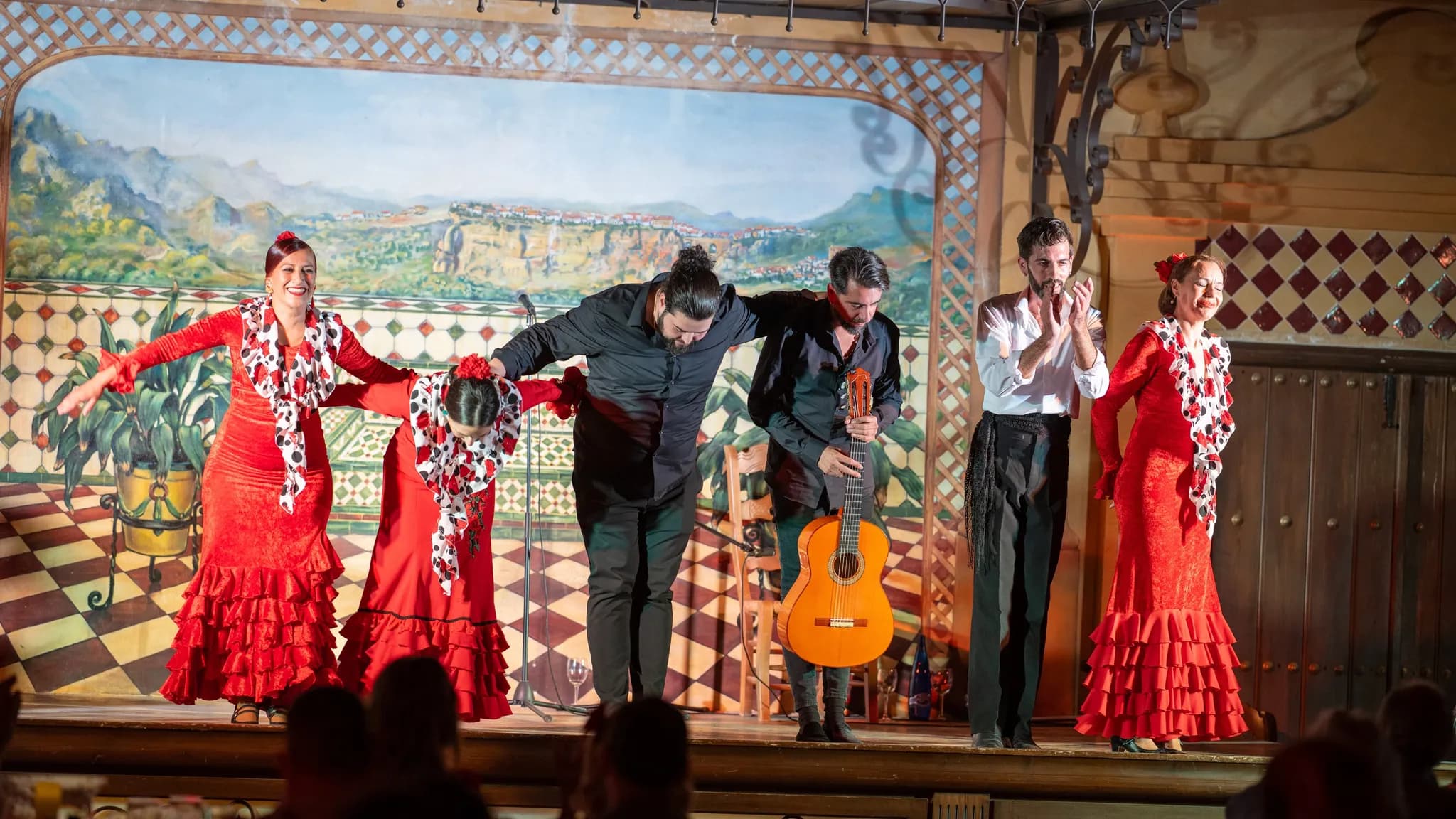 Flamenco dancers in red ruffled dresses and musicians taking a bow at the end of a show