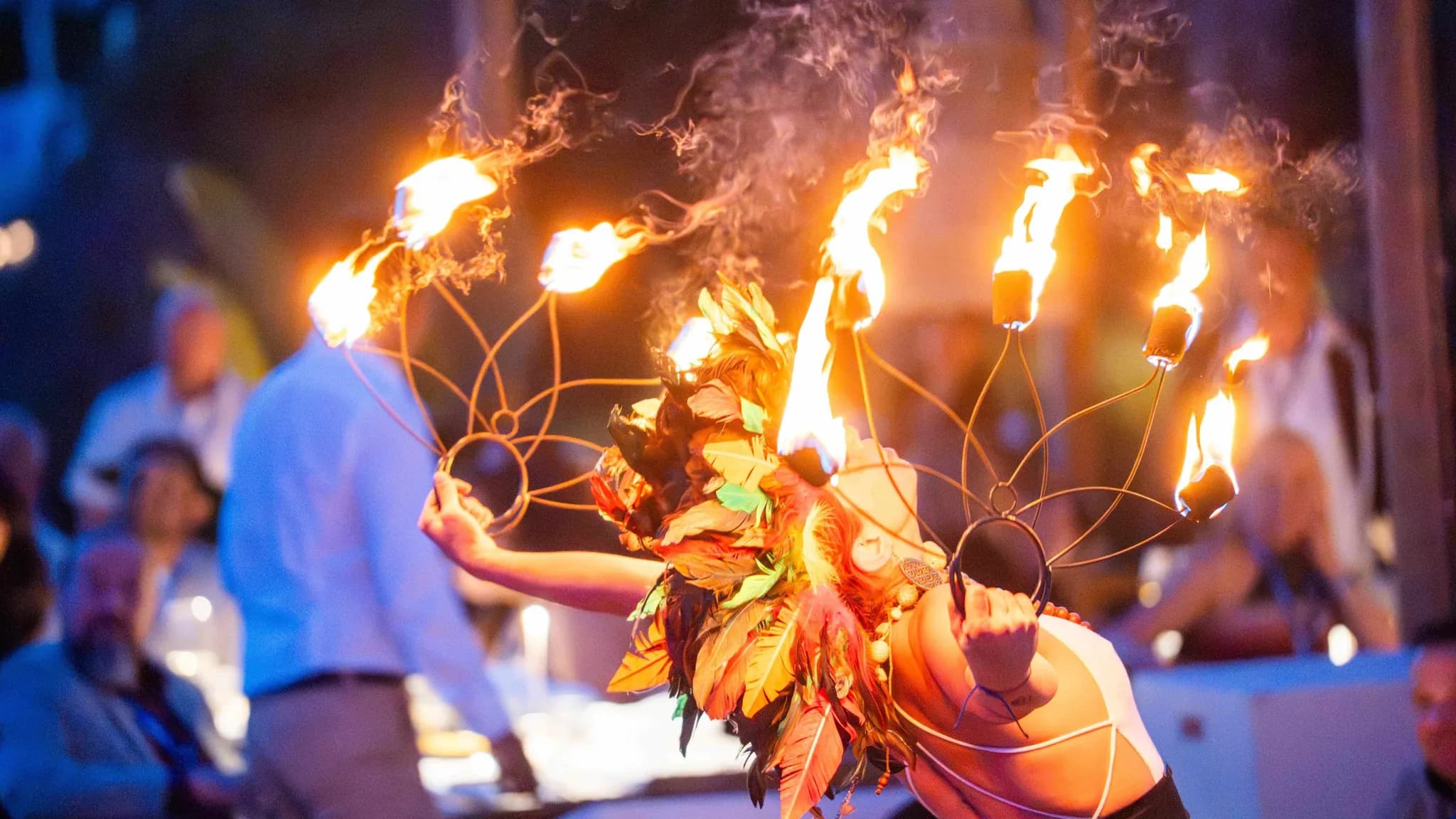 A fire performer in a leaf costume with a flaming headdress entertaining guests at an evening event